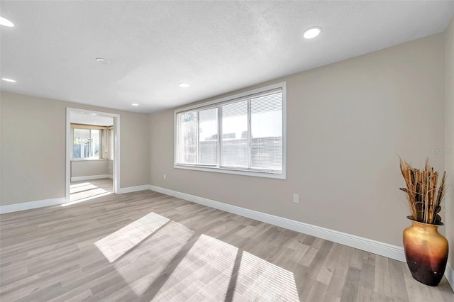 spare room with a textured ceiling and light wood-type flooring