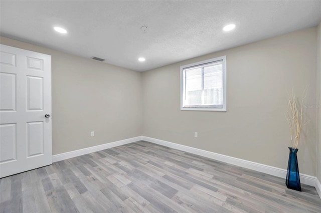 empty room featuring a textured ceiling and light wood-type flooring