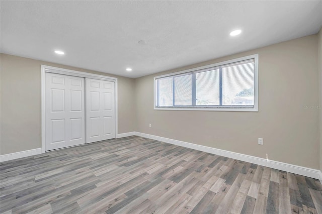 unfurnished bedroom with a closet, a textured ceiling, and light hardwood / wood-style flooring