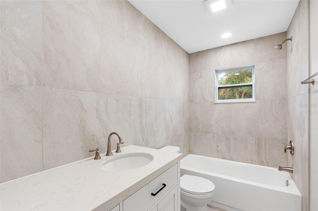 full bathroom featuring vanity, tiled shower / bath combo, tile walls, and toilet