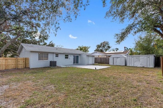 back of house with a lawn, a patio area, central AC, and a storage unit