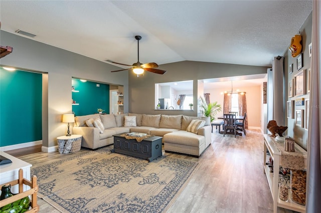 living room with a textured ceiling, hardwood / wood-style floors, ceiling fan with notable chandelier, and vaulted ceiling