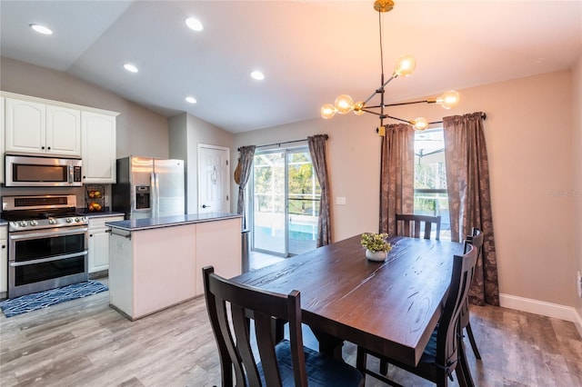 dining room featuring an inviting chandelier, light hardwood / wood-style flooring, and vaulted ceiling