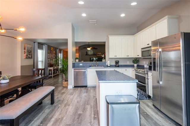 kitchen featuring stainless steel appliances, ceiling fan, sink, a center island, and light hardwood / wood-style floors