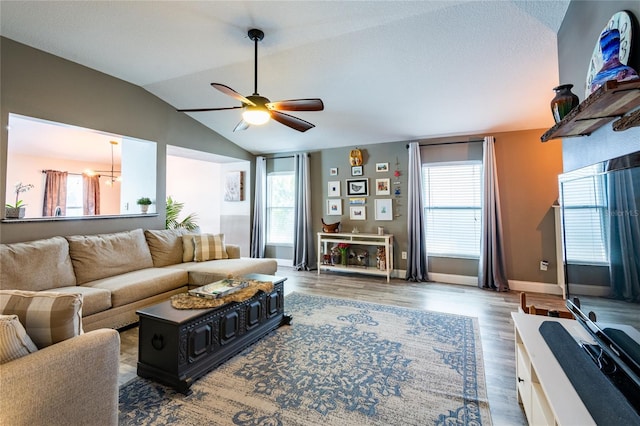 living room with hardwood / wood-style floors, ceiling fan with notable chandelier, and lofted ceiling