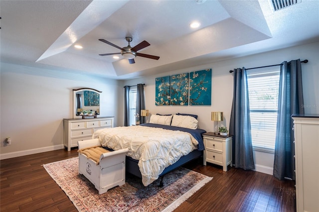 bedroom featuring a tray ceiling, ceiling fan, and dark wood-type flooring