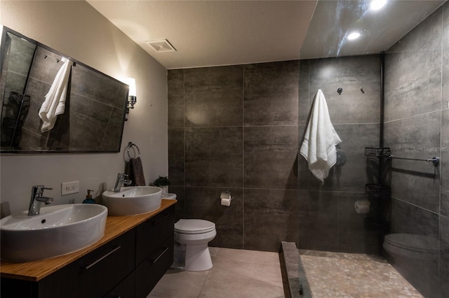 bathroom featuring tile patterned flooring, vanity, toilet, and tile walls