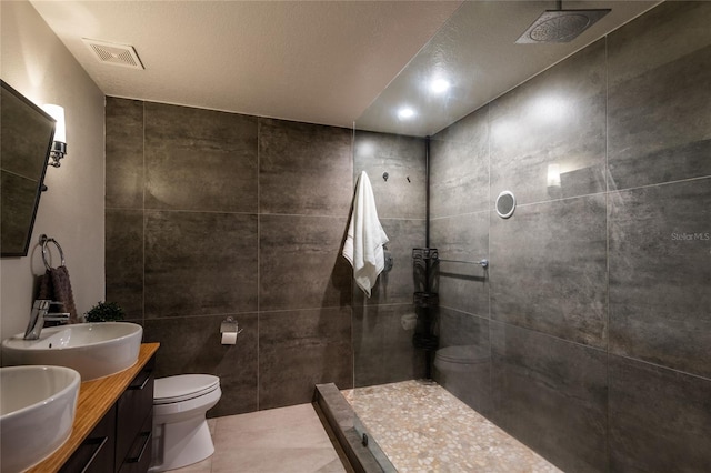 bathroom featuring tiled shower, tile walls, a textured ceiling, and toilet