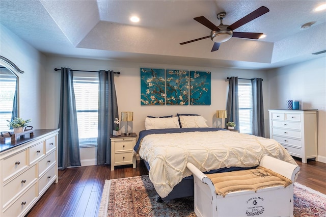 bedroom featuring a raised ceiling, ceiling fan, and dark hardwood / wood-style floors