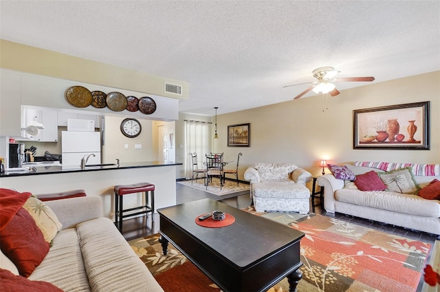 living room featuring a textured ceiling and ceiling fan