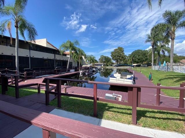 view of community featuring a boat dock, a water view, and a yard