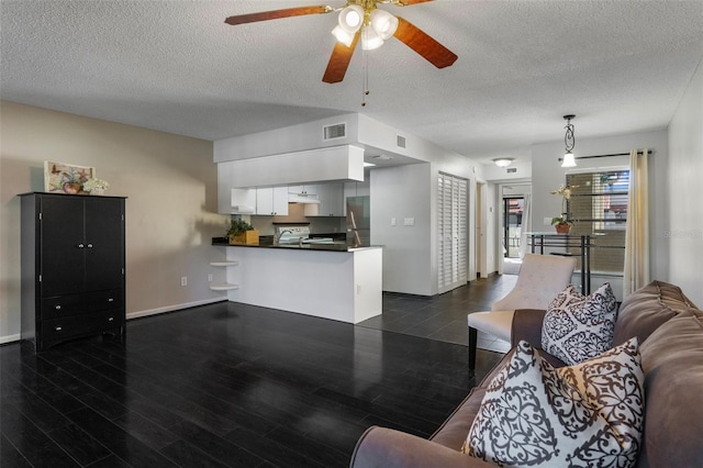 living room featuring visible vents, a textured ceiling, baseboards, ceiling fan, and dark wood-style flooring