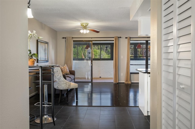 interior space with ceiling fan, dark tile patterned floors, and a textured ceiling