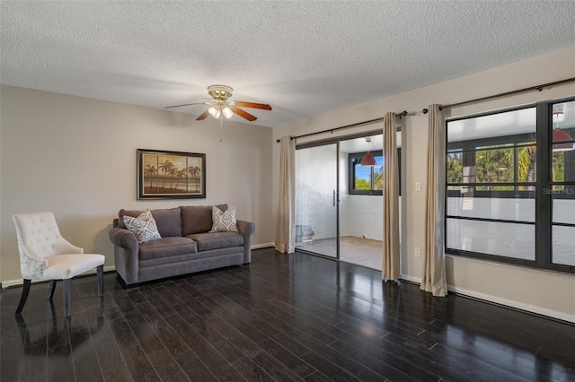 living room with a textured ceiling, baseboards, and wood finished floors