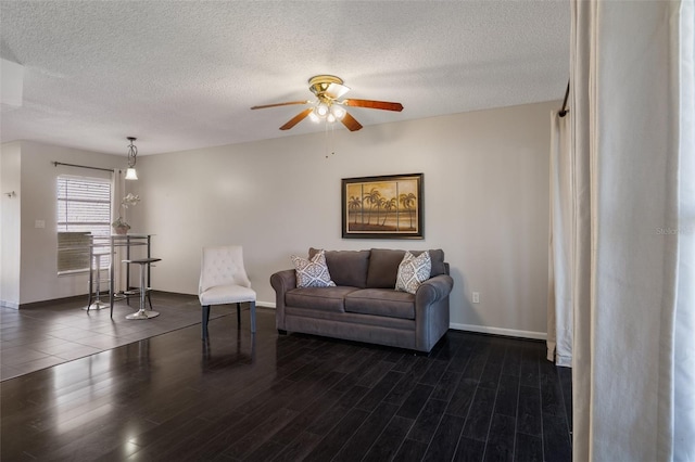 living area with baseboards, a textured ceiling, dark wood finished floors, and a ceiling fan