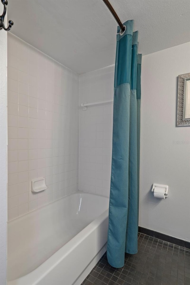 full bath with tile patterned flooring, shower / bath combo, baseboards, and a textured ceiling