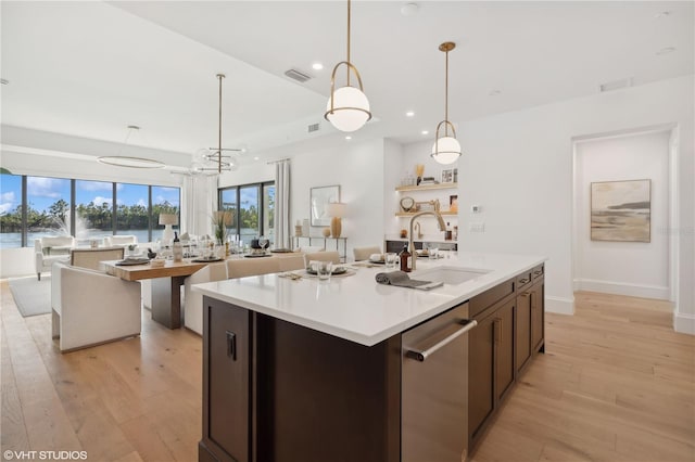 kitchen featuring sink, dishwasher, pendant lighting, a center island with sink, and light wood-type flooring