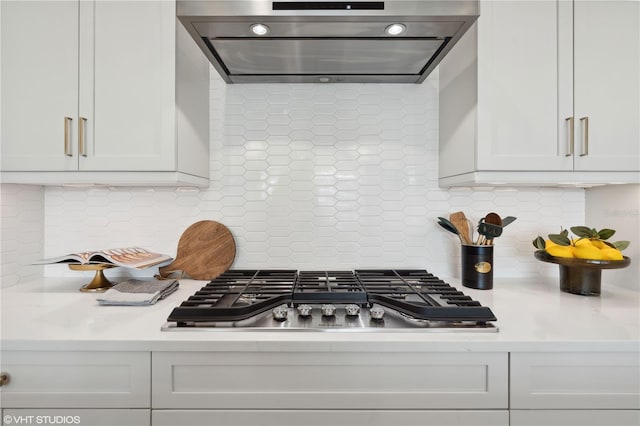 kitchen with decorative backsplash, white cabinets, extractor fan, and stainless steel gas cooktop