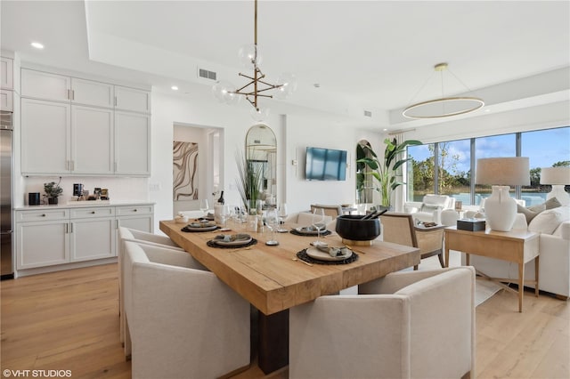 dining area with light hardwood / wood-style floors and an inviting chandelier