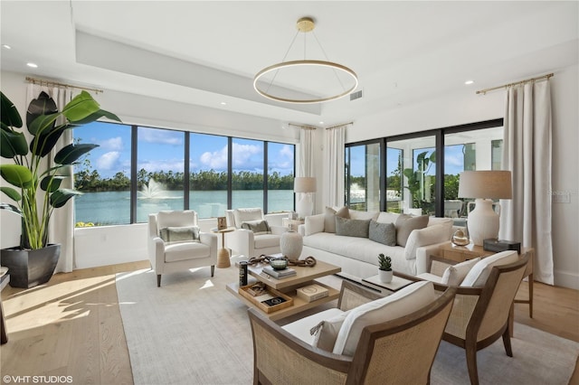 sunroom featuring a tray ceiling and a water view