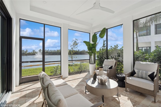 sunroom featuring ceiling fan and a water view