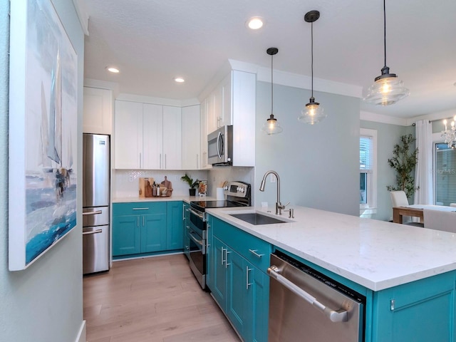 kitchen with white cabinetry, decorative light fixtures, blue cabinets, and appliances with stainless steel finishes