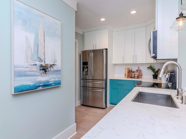 kitchen featuring appliances with stainless steel finishes, decorative light fixtures, blue cabinets, white cabinetry, and sink