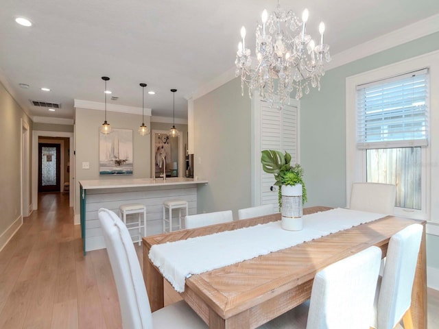 dining area featuring sink, crown molding, and light wood-type flooring