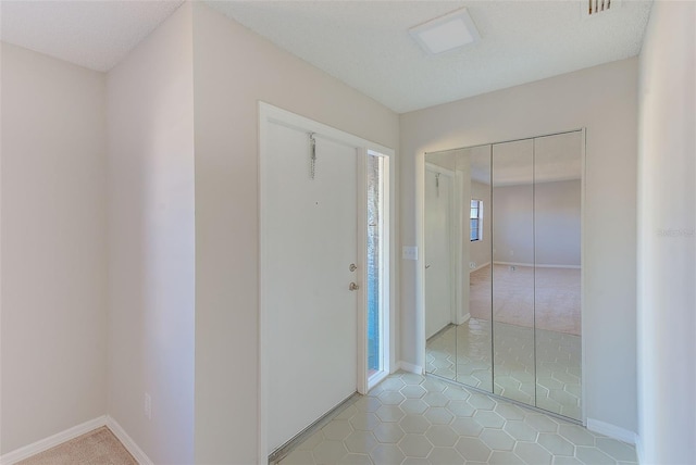 corridor with light tile patterned flooring, a textured ceiling, and a wealth of natural light