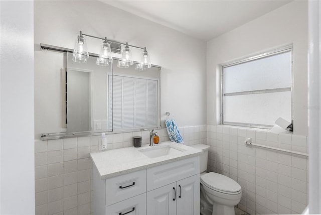 bathroom featuring toilet, vanity, and tile walls