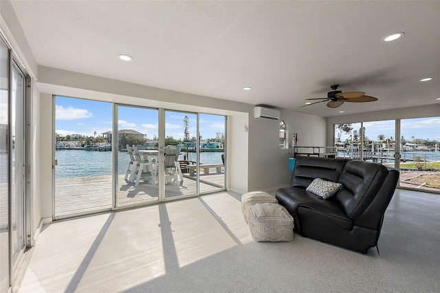 carpeted living room featuring ceiling fan, a water view, and a wall mounted air conditioner