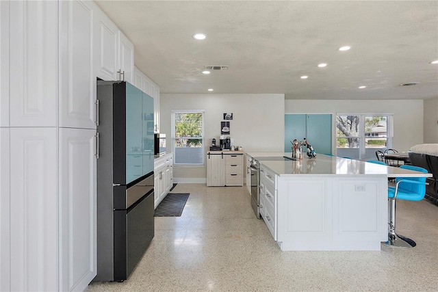 kitchen with a breakfast bar, appliances with stainless steel finishes, white cabinets, and a spacious island