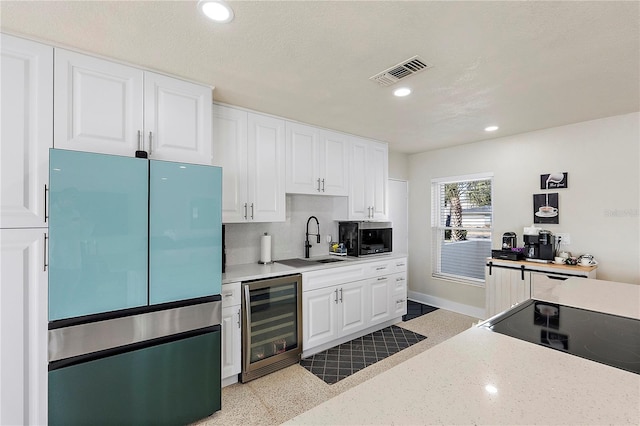 kitchen with sink, refrigerator, beverage cooler, and white cabinetry