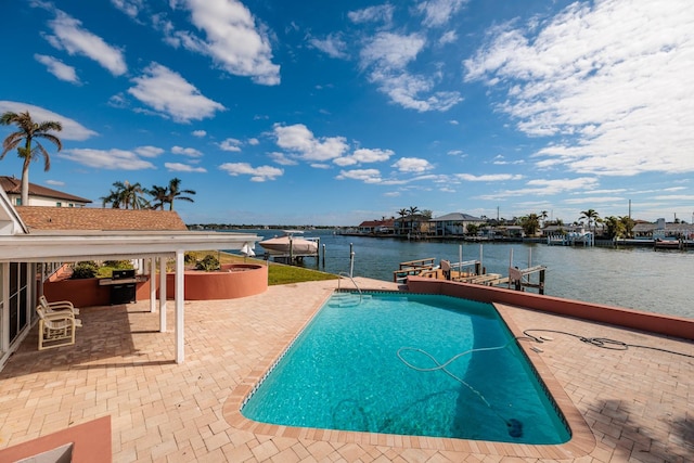 view of swimming pool featuring a water view, a patio area, and a boat dock