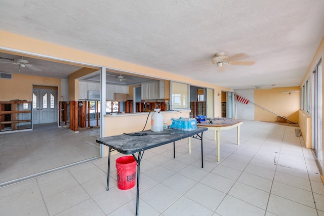 recreation room with ceiling fan, light tile patterned floors, and a textured ceiling