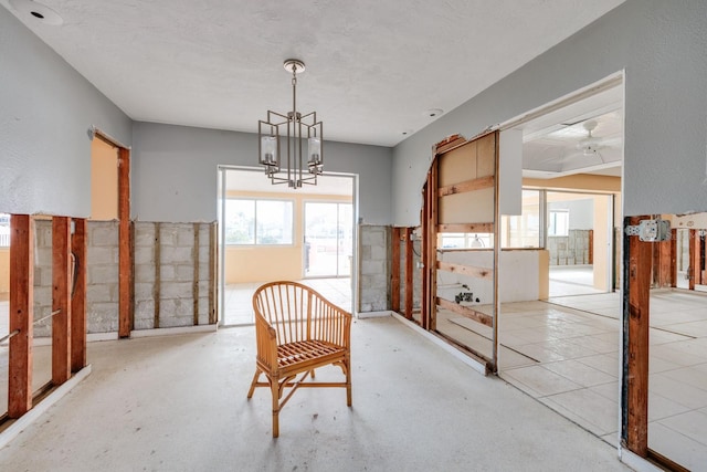 dining space featuring ceiling fan with notable chandelier and a textured ceiling