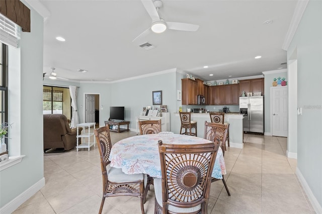 tiled dining space featuring ceiling fan and ornamental molding