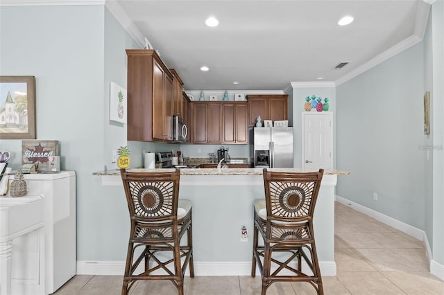 kitchen with stainless steel appliances, washer / clothes dryer, crown molding, kitchen peninsula, and a breakfast bar area