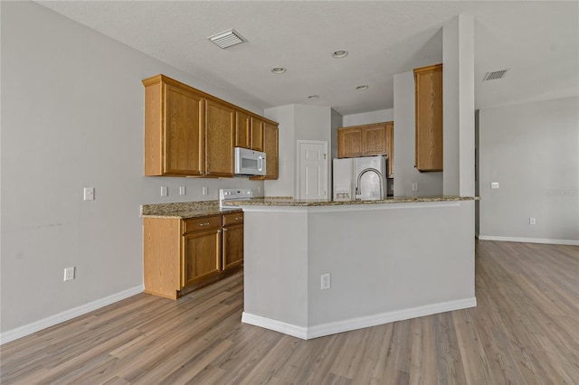 kitchen featuring white appliances, light hardwood / wood-style flooring, and light stone countertops