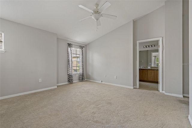 unfurnished room with light colored carpet, ceiling fan, and vaulted ceiling