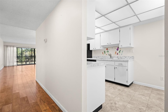 kitchen with white cabinetry, sink, and light hardwood / wood-style flooring