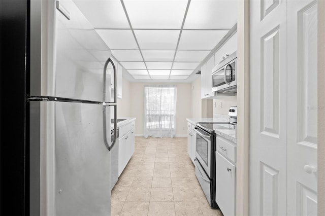 kitchen featuring a drop ceiling, white cabinets, light tile patterned floors, and appliances with stainless steel finishes