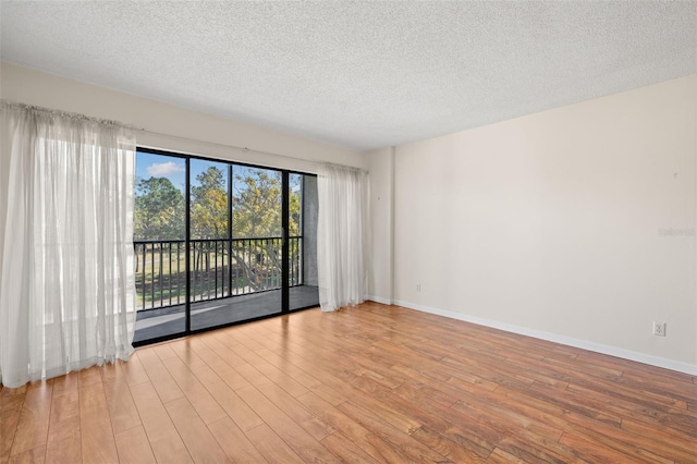 spare room with a textured ceiling and light hardwood / wood-style floors