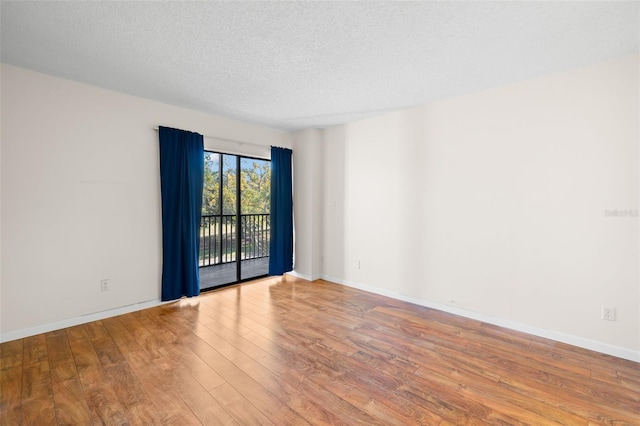 spare room with light hardwood / wood-style floors and a textured ceiling