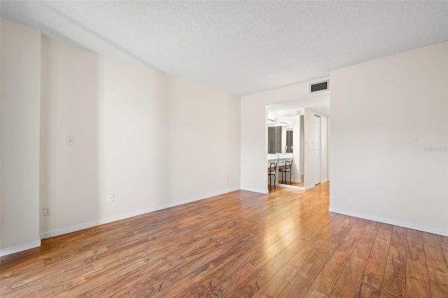 empty room with light hardwood / wood-style floors and a textured ceiling