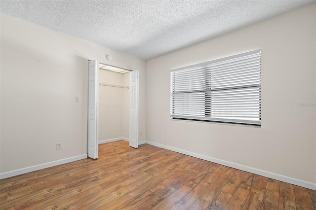 unfurnished bedroom with wood-type flooring, a textured ceiling, and a closet