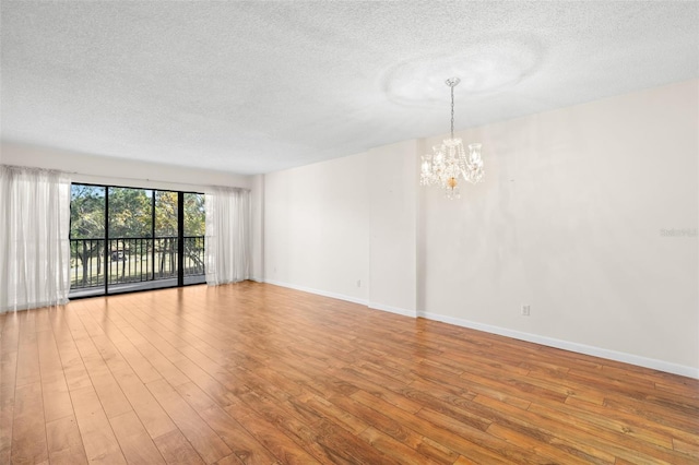 spare room featuring light hardwood / wood-style flooring, a textured ceiling, and an inviting chandelier