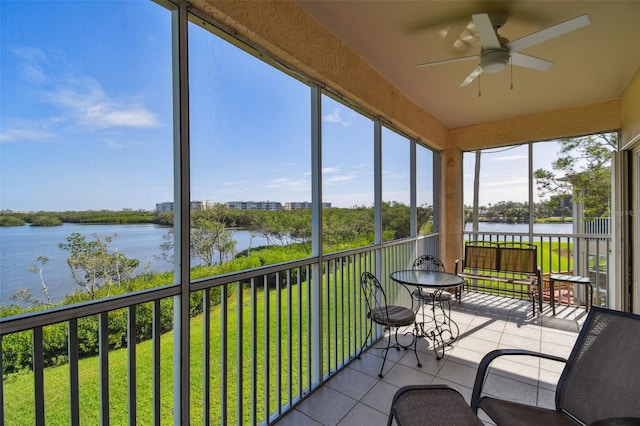 sunroom featuring ceiling fan and a water view