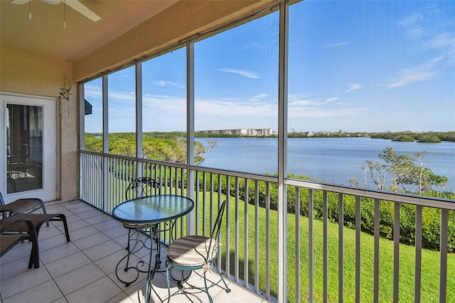 sunroom featuring ceiling fan and a water view