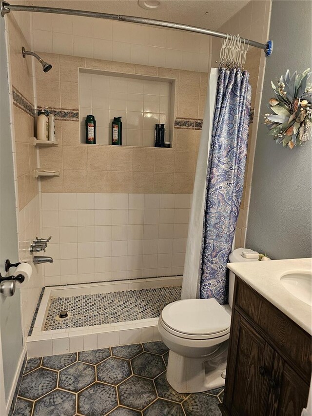 bathroom featuring tile patterned floors, walk in shower, vanity, and toilet